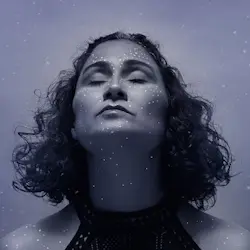 Artistic photograph of Janete Suely, radiating inner peace and introspection while displaying colourful oracle cards, reflecting the transformative experience of Jussara Valente’s sessions.